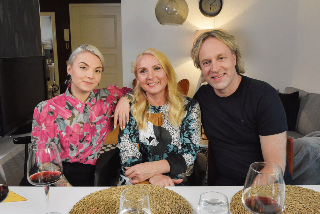 Veronica Verho istuu äitinsä Anneli Verhon ja Kape Aihisen kanssa ruokapöydän ääressä yhteiskuvassa